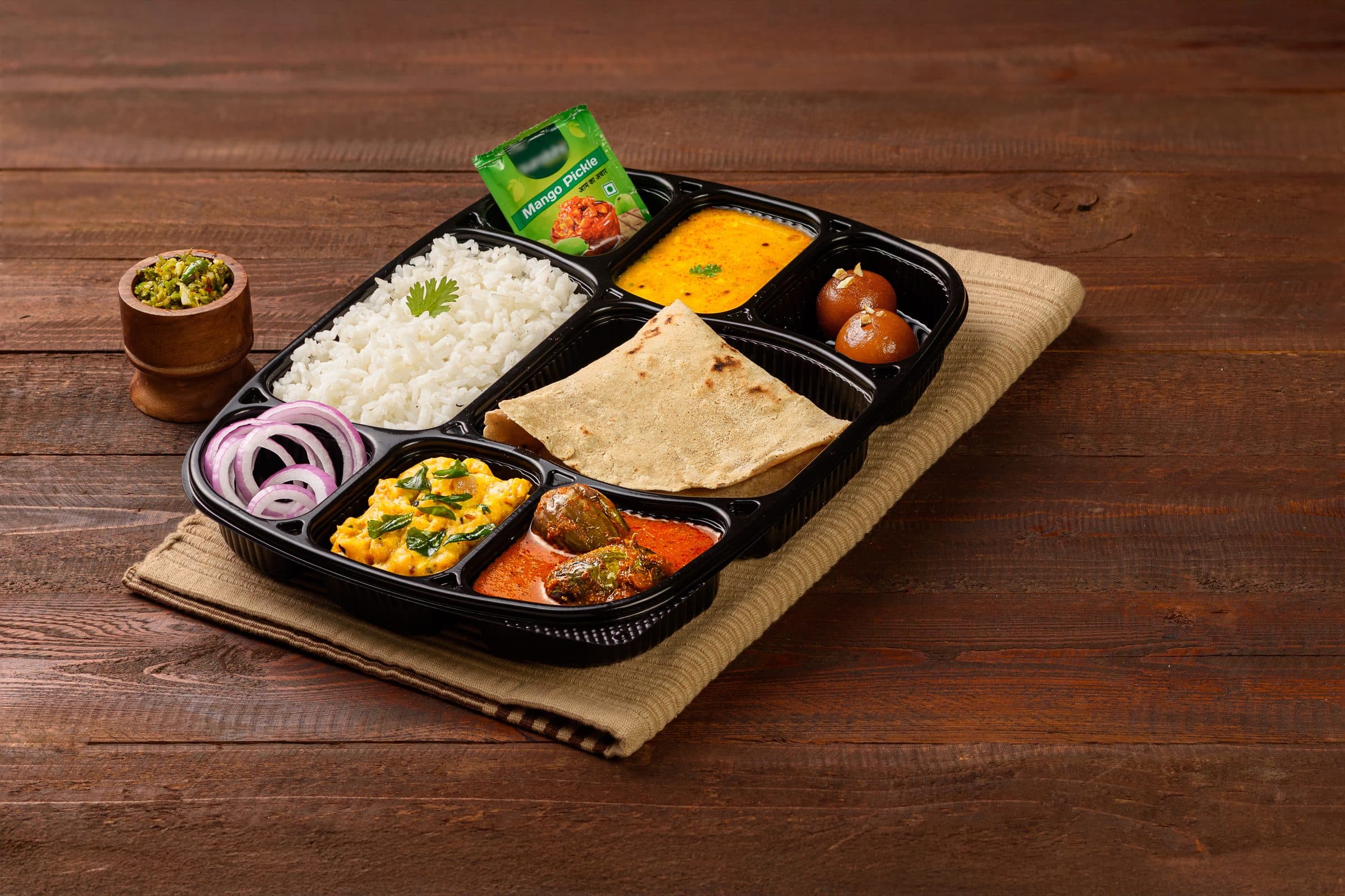 A Quantity Kitchens meal tray: steamed rice, bhakri, pithala, bharli vangi, dal, sliced onion, mango pickle and gulab jamun